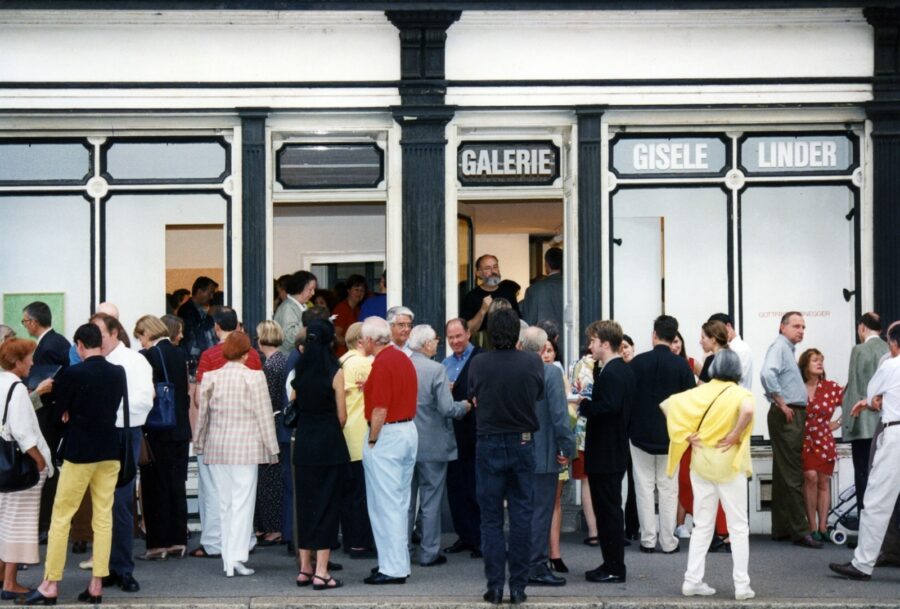Auf dem Trottoir stehen viele Leute in sommerlicher Kleider vor der Galerie Gisèle Linder.